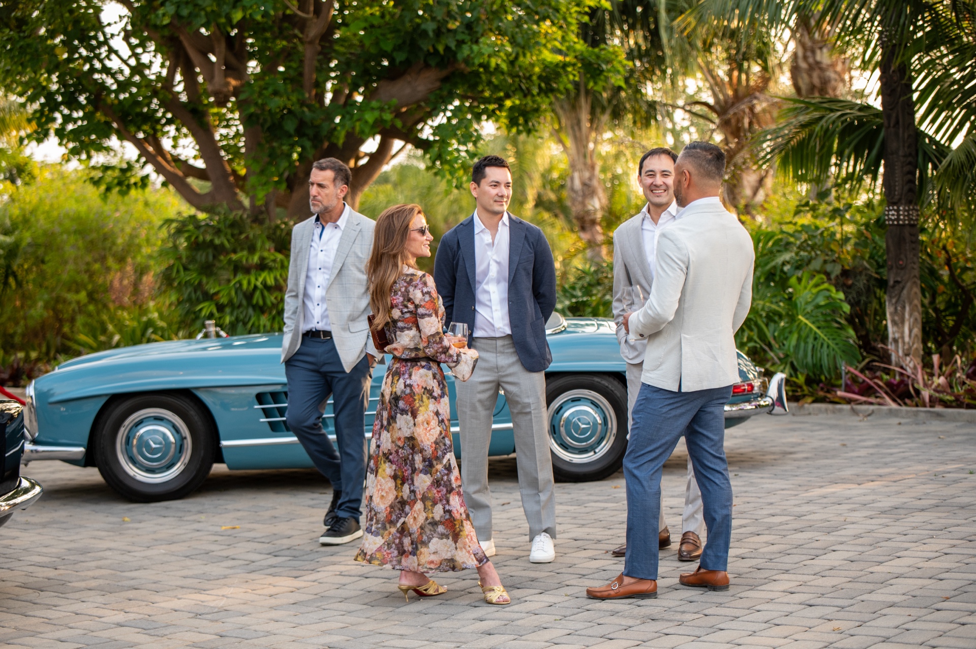 Guests gathering beside a classic blue automobile at the Vineyard showcase
